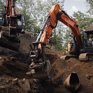 Excavator digging trenches for utility installation on a civil construction project in Massachusetts